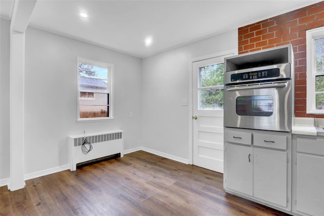 30 Inwood Rd, Glen Cove, NY 11542 - kitchen with radiator, a healthy amount of sunlight, wood finished floors, and stainless steel oven
