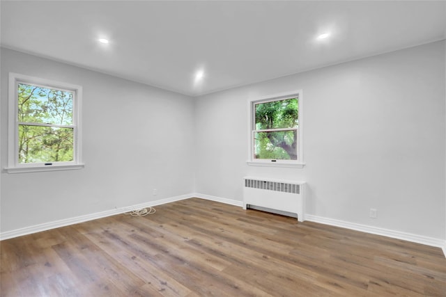 30 Inwood Rd, Glen Cove, NY 11542 - empty room with wood finished floors, baseboards, a healthy amount of sunlight, and radiator heating unit
