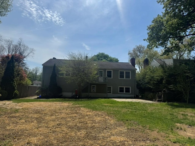 view of front of house featuring a patio, fence, a chimney, and a front yard