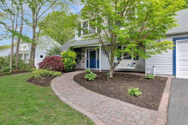 view of property hidden behind natural elements with a porch, a front yard, a garage, and roof with shingles