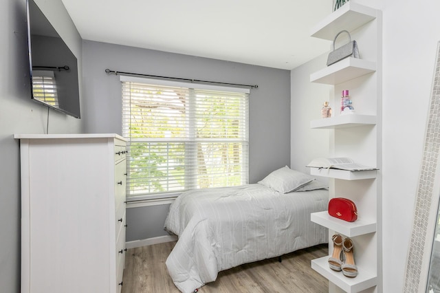 bedroom featuring light wood finished floors, multiple windows, and baseboards