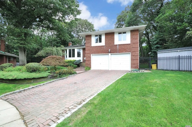 tri-level home featuring fence, a front yard, decorative driveway, brick siding, and an attached garage