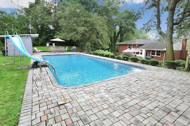 outdoor pool with a patio, a playground, a water slide, a yard, and outdoor dining space