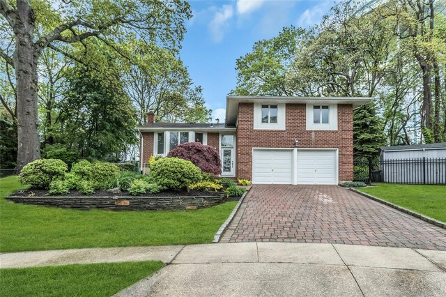31 Elmwood Ct, Plainview, NY 11803 - tri-level home with decorative driveway, brick siding, an attached garage, and a chimney