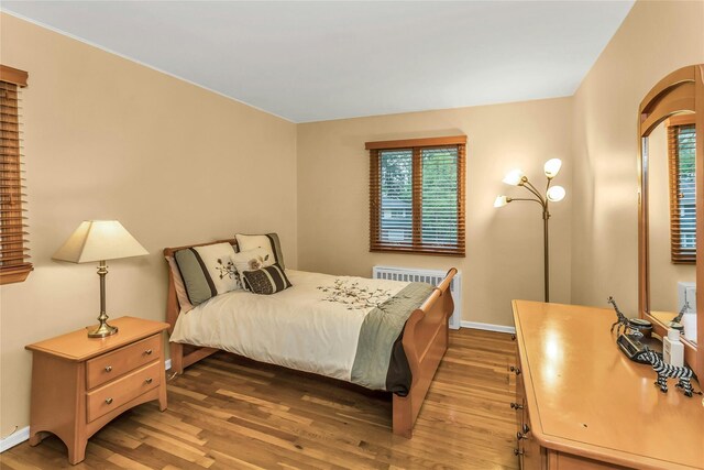 31 Elmwood Ct, Plainview, NY 11803 - bedroom featuring wood finished floors, radiator heating unit, baseboards, and arched walkways