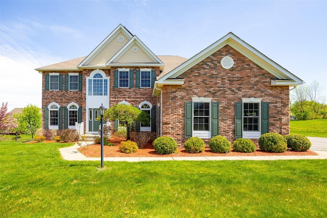 colonial-style house featuring brick siding and a front yard