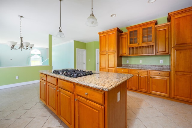 kitchen featuring light tile patterned floors, a center island, stainless steel gas cooktop, and a notable chandelier