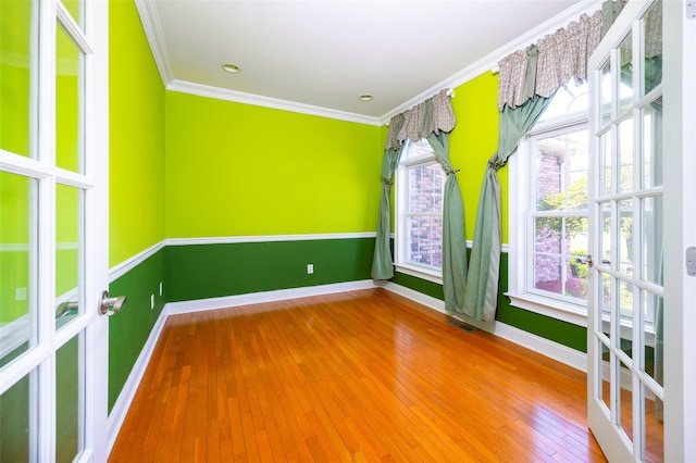 spare room with crown molding, baseboards, visible vents, and wood-type flooring