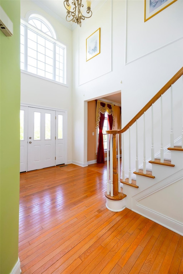 entrance foyer with stairs, a high ceiling, a chandelier, and light wood-style flooring