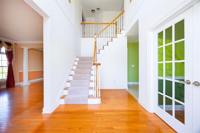 stairs with wood-type flooring, baseboards, and crown molding