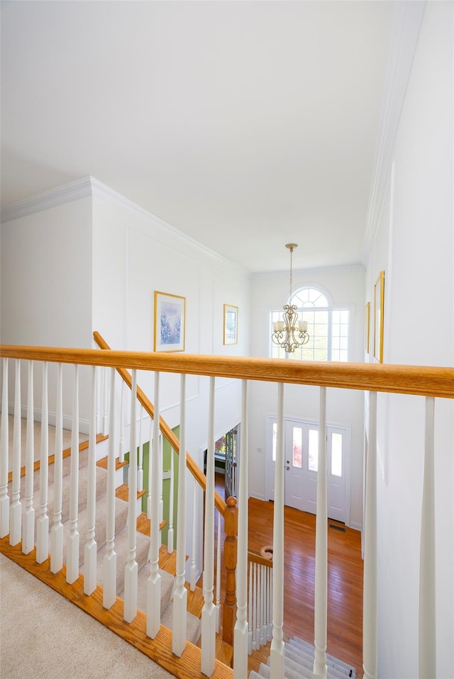 stairs featuring crown molding and a chandelier