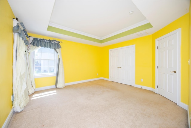 unfurnished bedroom featuring crown molding, carpet, and a raised ceiling