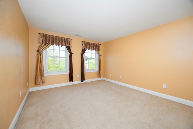 spare room with baseboards, visible vents, and light carpet