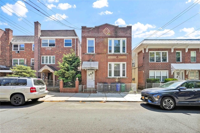 multi unit property with brick siding and a fenced front yard
