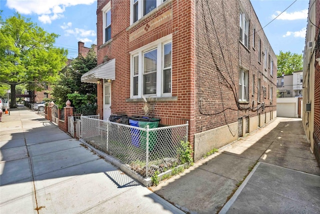 view of property exterior with brick siding and fence
