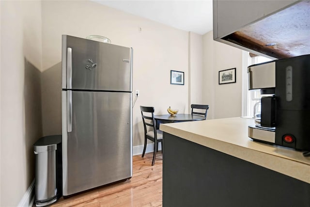 kitchen featuring baseboards, freestanding refrigerator, light wood-style flooring, and light countertops