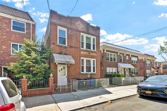 townhome / multi-family property featuring a residential view, a fenced front yard, and brick siding