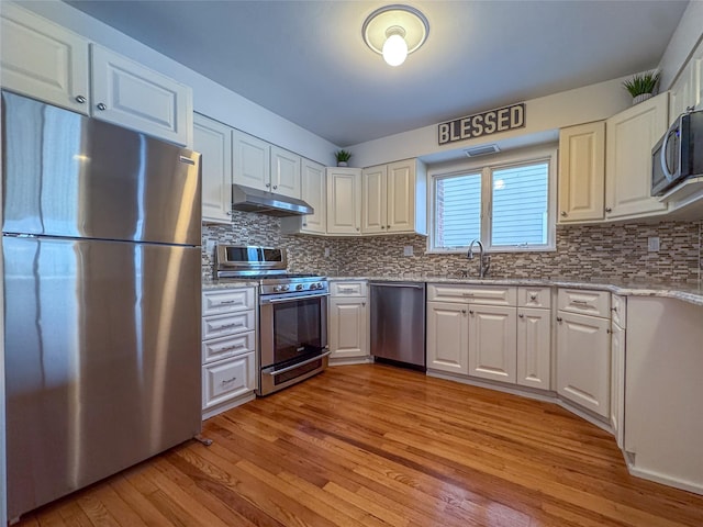 208 Block Ln, Harbor Isle, NY 11558 - kitchen with stainless steel appliances, under cabinet range hood, light wood-style floors, a sink, and light stone counters