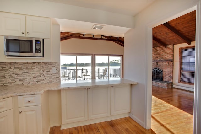 208 Block Ln, Harbor Isle, NY 11558 - kitchen featuring stainless steel microwave, decorative backsplash, light wood-style floors, light stone counters, and white cabinets
