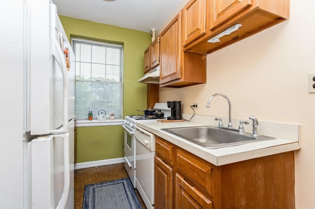 kitchen featuring white appliances, a sink, under cabinet range hood, light countertops, and baseboards
