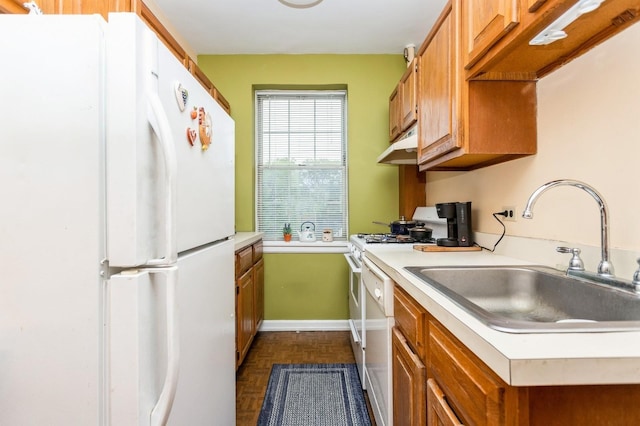 kitchen featuring white appliances, a sink, light countertops, and brown cabinets