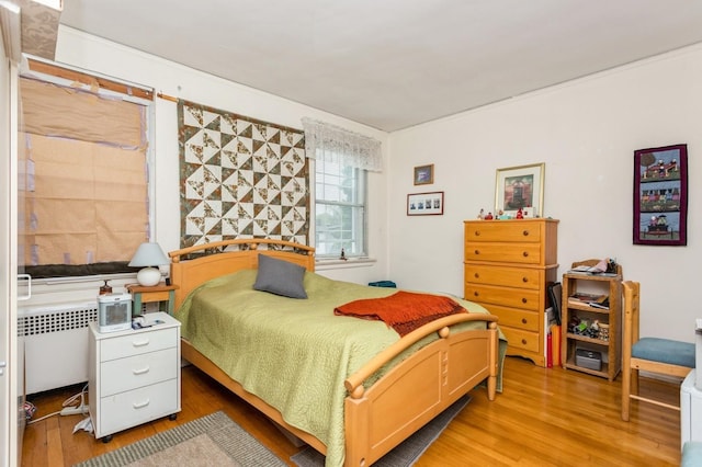 bedroom featuring radiator heating unit and light wood-style floors