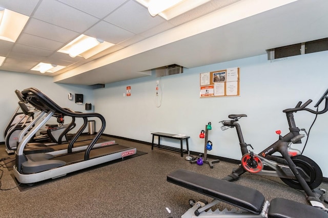 exercise room featuring baseboards and a paneled ceiling