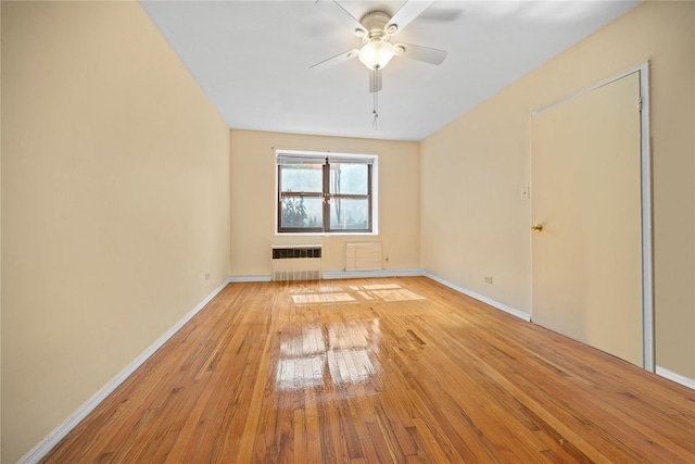 unfurnished room with light wood-style floors, radiator, baseboards, and a ceiling fan
