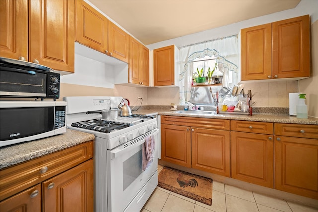 kitchen featuring brown cabinets, a sink, white appliances, light tile patterned floors, and tasteful backsplash