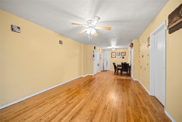 interior space with a ceiling fan, baseboards, and light wood-style flooring