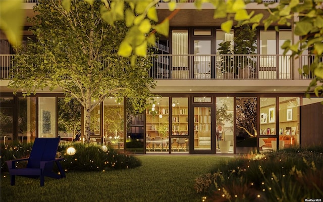back of house with a lawn and a balcony