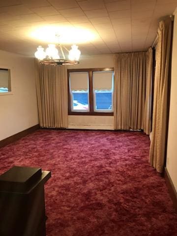 carpeted empty room with baseboards and a chandelier