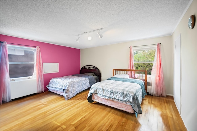 211 Cantiague Rock Rd, Westbury, NY 11590 - bedroom featuring rail lighting, a textured ceiling, and wood-type flooring