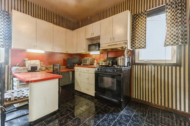 84-52 123rd St, Kew Gardens, NY 11415 - kitchen with black appliances, wallpapered walls, under cabinet range hood, cream cabinets, and a peninsula