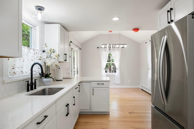 kitchen with freestanding refrigerator, a sink, baseboard heating, light wood-style flooring, and a chandelier