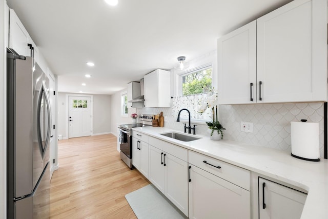 kitchen featuring stainless steel appliances, a sink, light wood-type flooring, white cabinets, and recessed lighting
