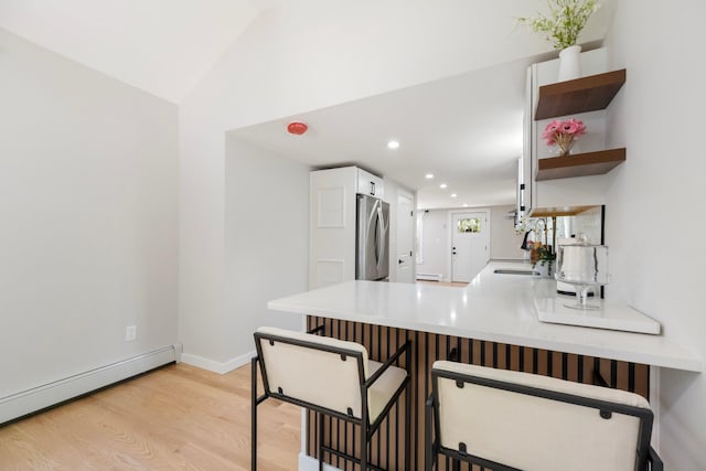 kitchen featuring freestanding refrigerator, a baseboard radiator, light wood-type flooring, white cabinetry, and recessed lighting