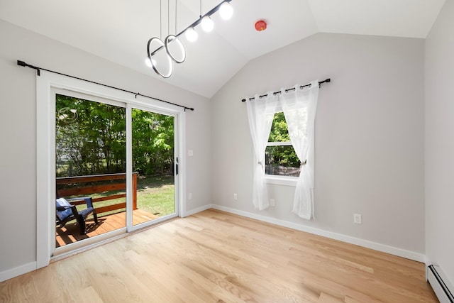 empty room featuring baseboard heating, lofted ceiling, healthy amount of natural light, light wood-type flooring, and baseboards