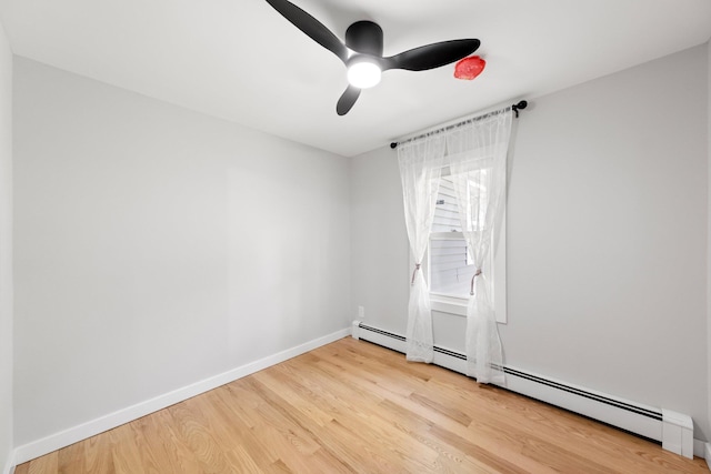 empty room with wood finished floors, baseboards, a ceiling fan, and a baseboard radiator
