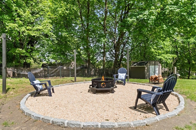 view of patio / terrace featuring an outdoor fire pit, a storage unit, fence, and an outbuilding