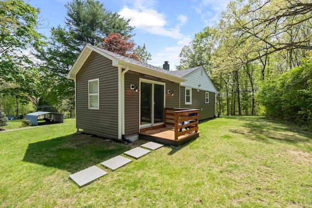rear view of house featuring a deck, a yard, a chimney, and a shingled roof