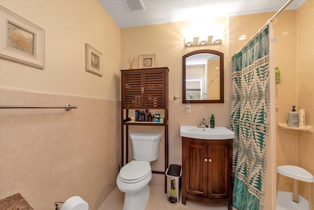 bathroom with tile walls, a shower with curtain, toilet, and vanity