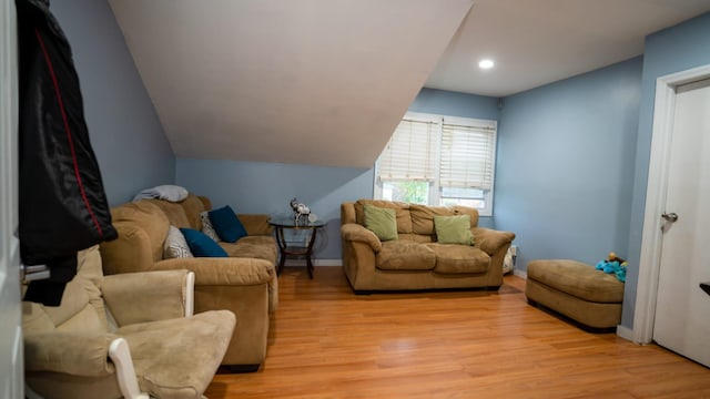 living area with light wood-type flooring, baseboards, and vaulted ceiling