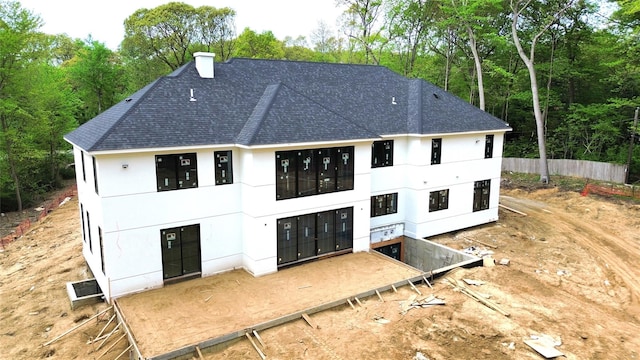 back of property with a chimney, stucco siding, and a shingled roof