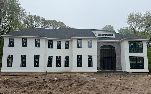 view of front of house featuring a shingled roof and stucco siding
