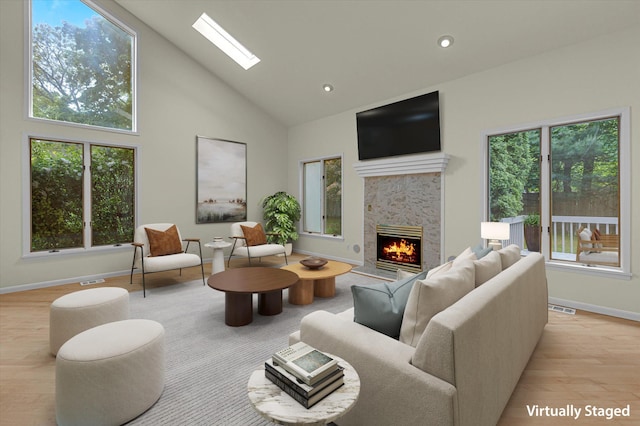 2 Heiko Ct, Northport, NY 11768 - living room with light wood-style flooring, high vaulted ceiling, a stone fireplace, a skylight, and baseboards