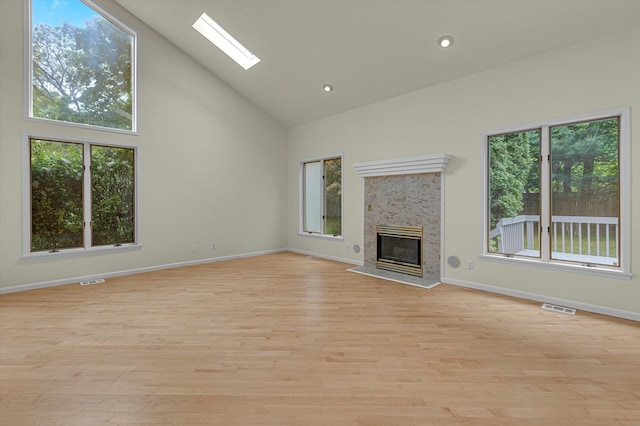 2 Heiko Ct, Northport, NY 11768 - unfurnished living room featuring high vaulted ceiling, a skylight, baseboards, a glass covered fireplace, and light wood-type flooring