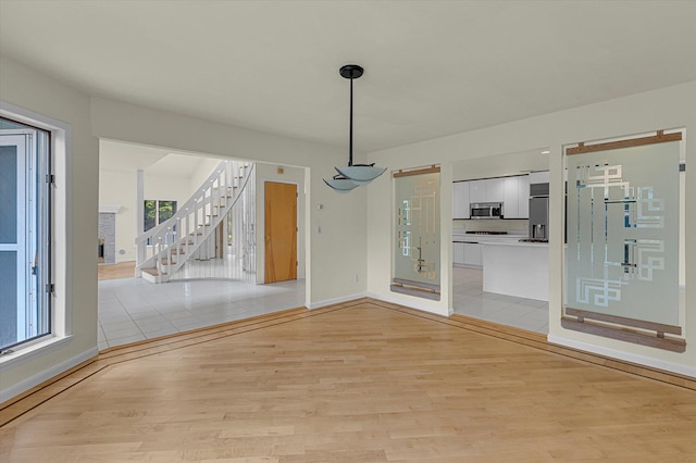 2 Heiko Ct, Northport, NY 11768 - unfurnished dining area with light wood finished floors, stairway, baseboards, and plenty of natural light