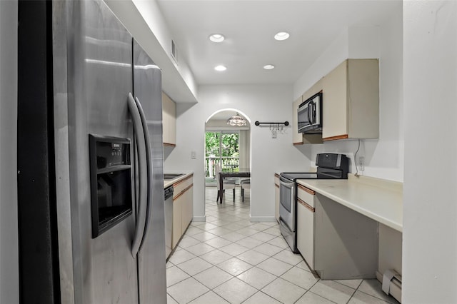 kitchen featuring appliances with stainless steel finishes, arched walkways, light tile patterned floors, light countertops, and a baseboard radiator