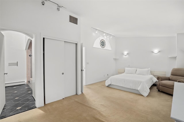 bedroom featuring track lighting, baseboard heating, arched walkways, carpet, and visible vents